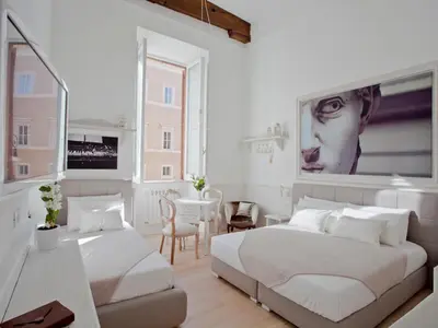 a white bedroom with two beds and a table at Primo Piano Suites in Rome