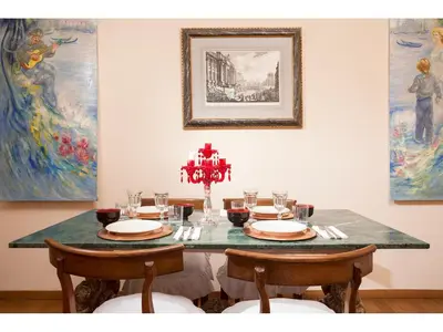 a dining room table with chairs and a table with plates and glasses at Apartment Margutta in Rome