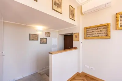 a hallway with white walls and a staircase with paintings on the wall at Argentina Penthouse by Rental in Rome in Rome