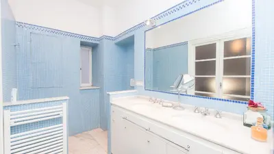 a blue tiled bathroom with a sink and a mirror at Rental in Rome Risorgimento view Aparment in Rome