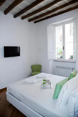 a white bedroom with a white bed with green accents at PgrHome Parione in Rome