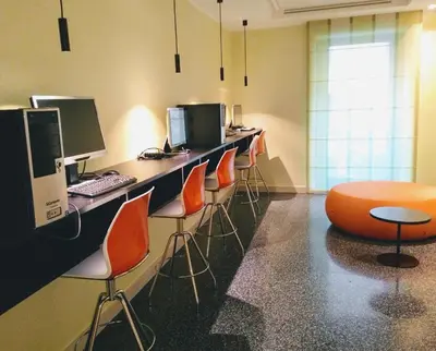 an office with a row of desks with computers and orange chairs at Domus Helena in Rome