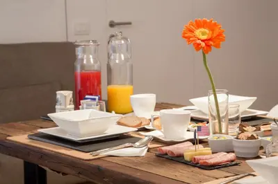 a table with plates and a vase with a flower at Belli36rooms near Spanish step and Vatican City in Rome