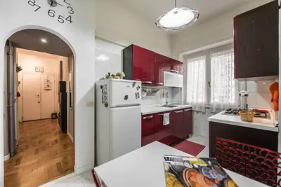 a kitchen with red cabinets and a white refrigerator at Modern Living San Paolo - Vicino alla Metro in Rome