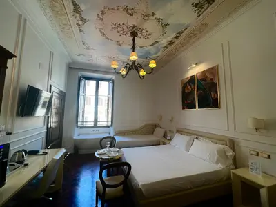 a bedroom with a bed and a table and a chandelier at Navona Central Suites in Rome