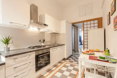 a kitchen with white cabinets and a table in it at MamaR Apartment in Rome