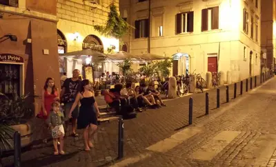 a group of people walking down a street at night at Viale del Colosseo in Rome