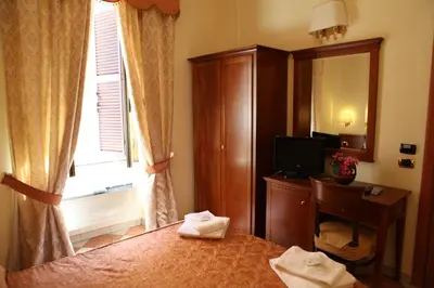 a bedroom with a bed and a desk and a window at Elegance in Rome
