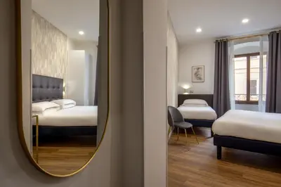 a hotel room with two beds and a mirror at Amalia Suites by Remember Rome in Rome