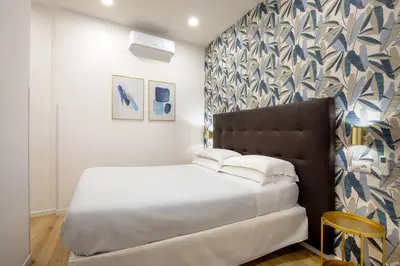 a bedroom with a white bed and a patterned wall at Amalia Suites by Remember Rome in Rome