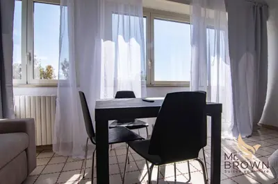 a table and chairs in a room with windows at Mr Brown Home and suites in Rome