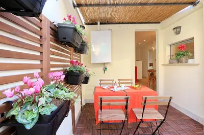 a patio with a table and chairs and flowers at Colosseum Stylish Apartment in Rome