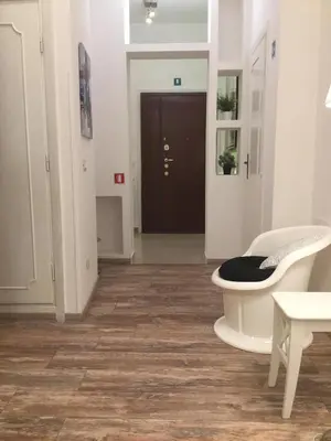 a living room with a wooden floor and a white chair at Maison Velia in Rome