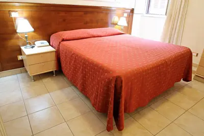 a bedroom with a bed with a red comforter and a phone at Rosetta in Rome