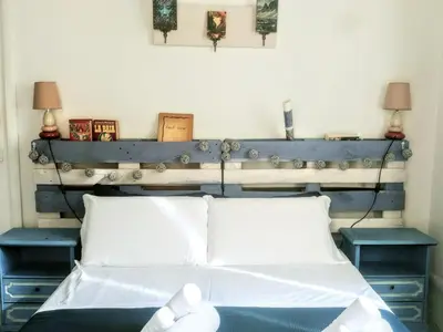 a bed with a blue headboard and two tables at B&B Next Stop in Rome