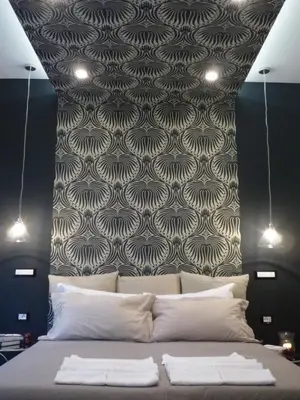 a bedroom with a bed with a patterned wall at Alma Mater B&B in Rome