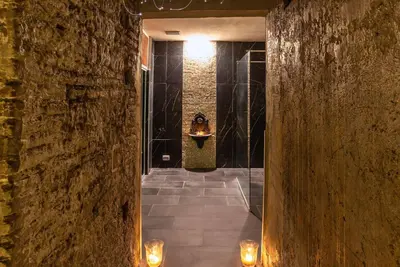 a hallway with a stone wall with lights and a sink at Ingrami Suites and Spa in Rome