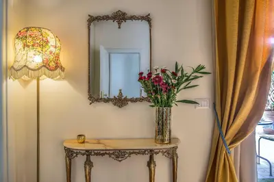 a vase of flowers on a table with a mirror at Ingrami Suites and Spa in Rome