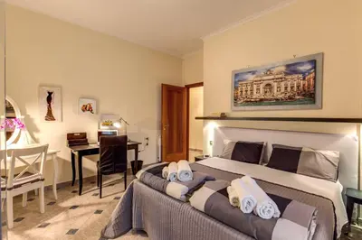 a bedroom with a large bed with a desk and a table at Residenza Amoroma in Rome