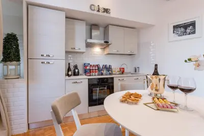 a white kitchen with a table with wine glasses and snacks at TownHouse by the Spanish Steps in Rome