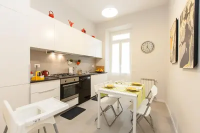 a kitchen with white cabinets and a table and chairs at Lovely House Rome in Rome