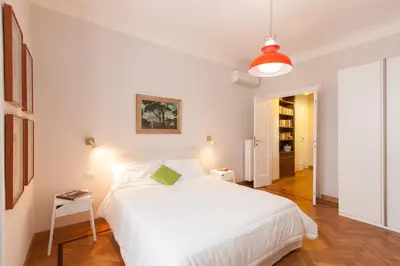 a white bedroom with a large white bed with a green pillow at Lovely House Rome in Rome