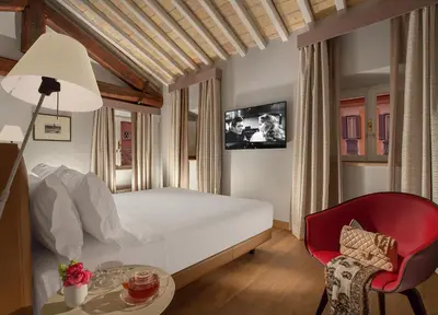 a bedroom with a white bed and a red chair at Palazzo Scanderbeg in Rome