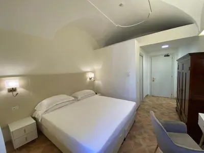 a bedroom with a large white bed and a chair at Basilica Hotel in Rome