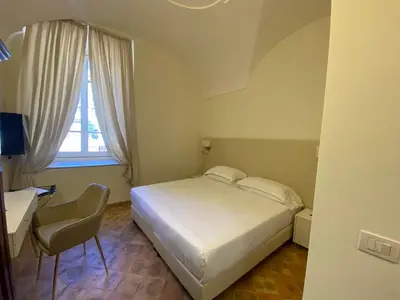 a bedroom with a bed and a desk and a window at Basilica Hotel in Rome
