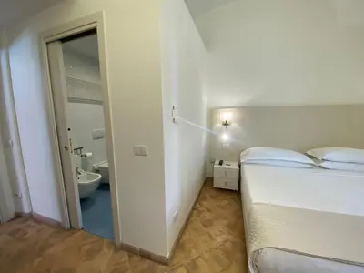 a white bedroom with a bed and a bathroom at Basilica Hotel in Rome