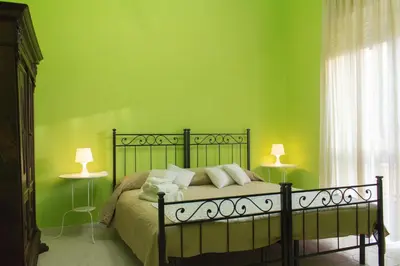 a bedroom with a bed with green walls and two lamps at Gli Alloggi Di Papà in Rome