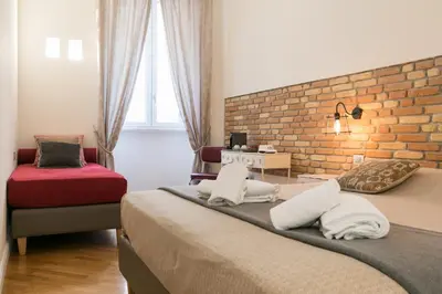 a bedroom with two beds and a brick wall at Spagna Ave in Rome