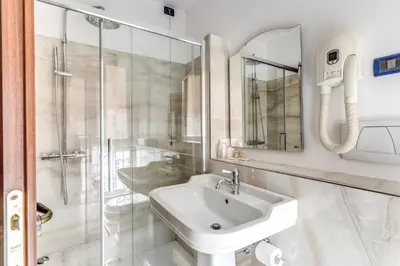a white bathroom with a sink and a shower at Residenza Ave Roma in Rome