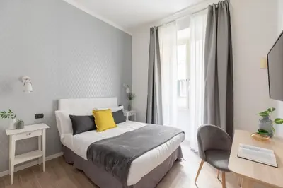 a bedroom with a bed with a yellow pillow and a desk at Residenza Vaticana in Rome