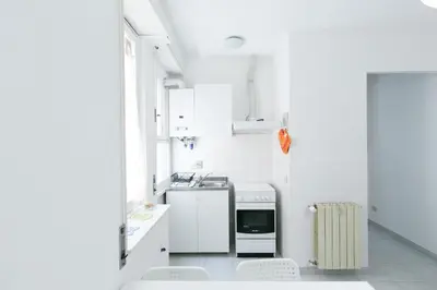 a white kitchen with white appliances and white cabinets at Domus Klimt in Rome