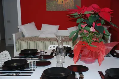 a dining room table with a vase with red flowers at Domus Klimt in Rome