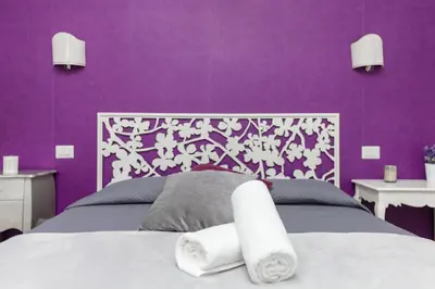 a purple bedroom with a bed with towels on it at Re di Luna B&B in Rome
