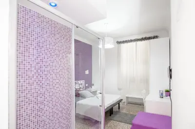 a bathroom with a pink tiled wall next to a bedroom at Re di Luna B&B in Rome