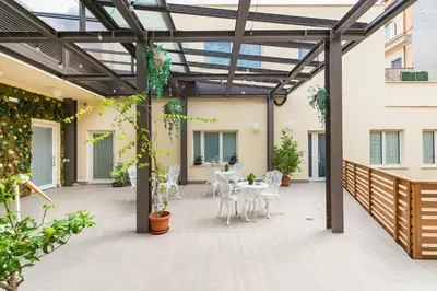 a patio with white chairs and tables and a glass roof at Borghetto Guest House in Rome