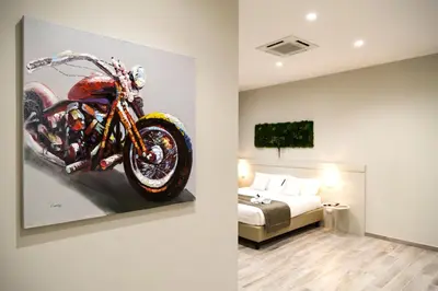 a painting of a motorcycle on a wall next to a bedroom at Borghetto Guest House in Rome