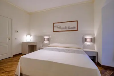 a white bedroom with a large white bed and two tables at Lory House in Rome