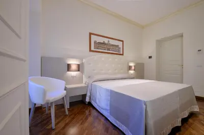 a white bedroom with a bed and a chair at Lory House in Rome