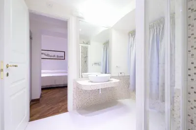 a white bathroom with a sink and a bed at Lory House in Rome