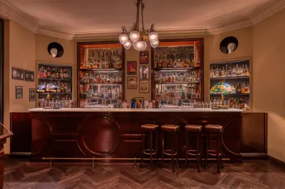 a bar with bar stools and shelves of alcohol at Hotel Locarno in Rome
