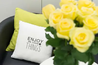 a pillow with the words enjoy the little things next to yellow roses at Casa Brunetti in Rome