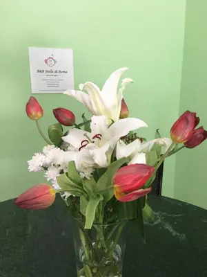 a vase filled with red and white flowers on a table at B&B Stelle Di Roma in Rome