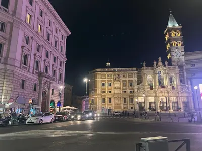 a city street at night with a building with a clock tower at Glam Sm Maggiore Guest House in Rome