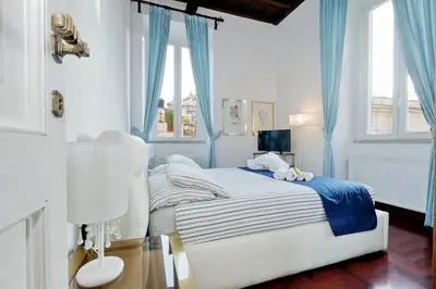 a bedroom with a white bed with blue curtains at Pantheon Family Romantic Suite in Rome