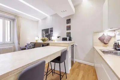 a kitchen with white walls and a counter with chairs at Campo dei Fiori modern apartment with terrace in Rome
