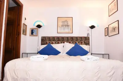 a bedroom with a large white bed with blue pillows at Agrippa's Terrace in Rome